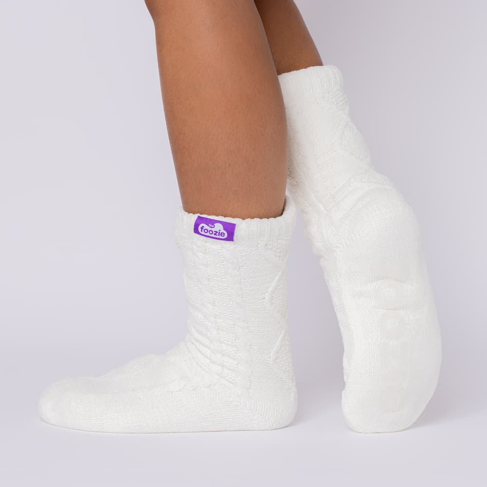The Foozie™ Move in White, side view with one heel raised, showing the diamond cable knit and the logo tab