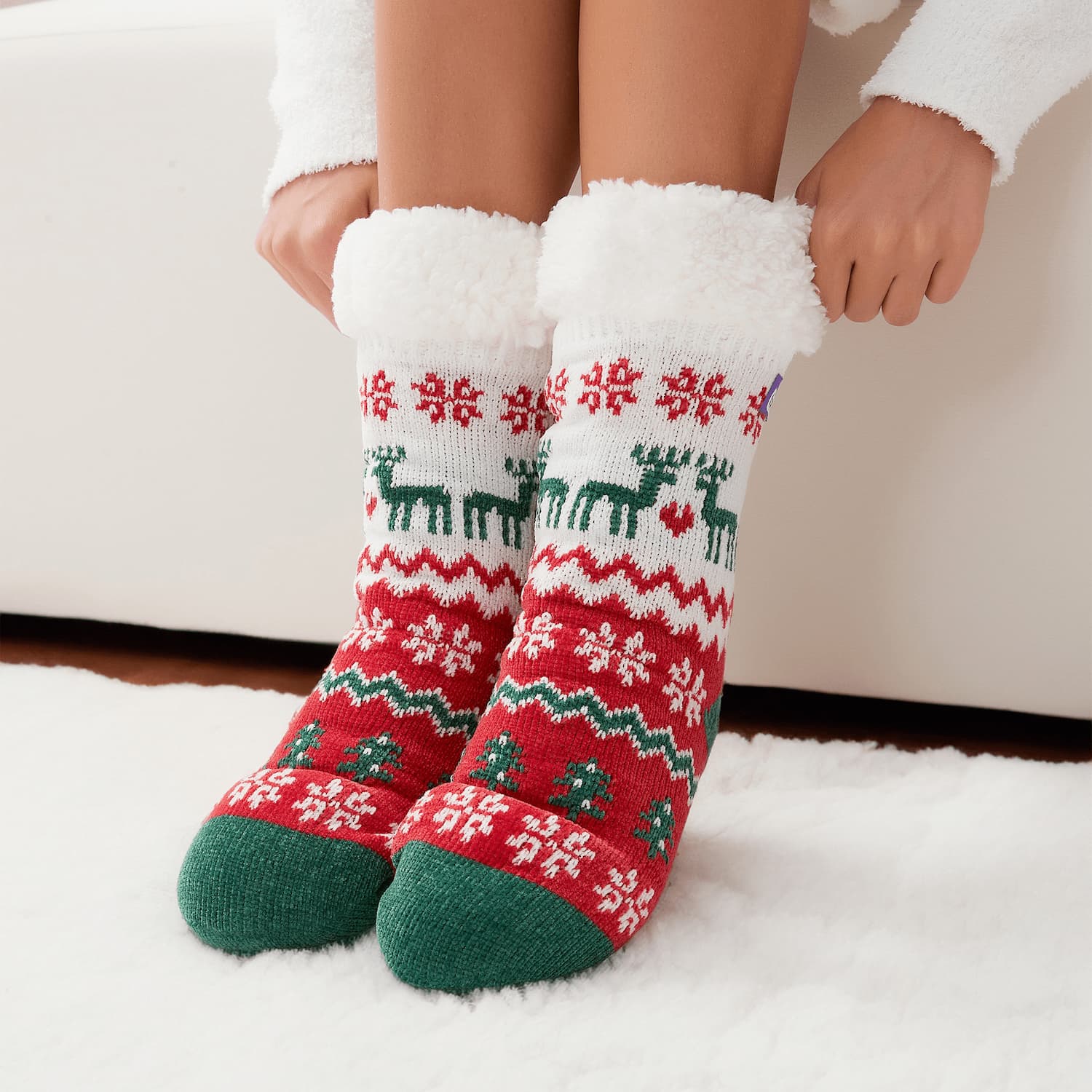 The Foozie™ Christmas Winterland, red, white and green reindeer and snowflake knit, hands pulling up the sherpa cuffs