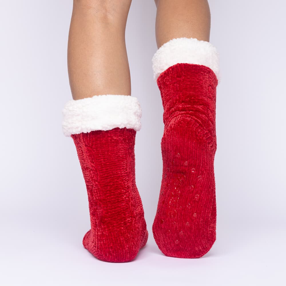 The Foozie™ in Red, back view with one foot raised to show the non-slip grips on the sole