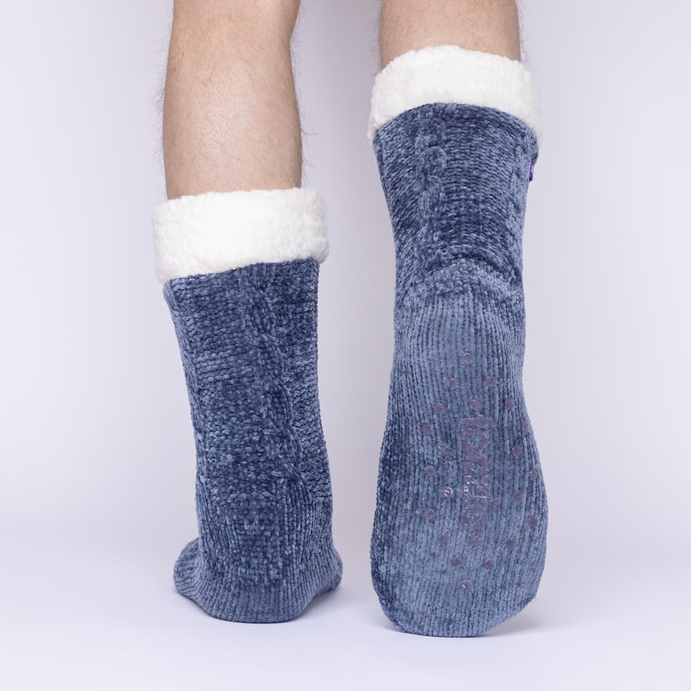 The Foozie™ in Blue, back view worn by a man in Large with one foot raised to show the non-slip grips on the sole