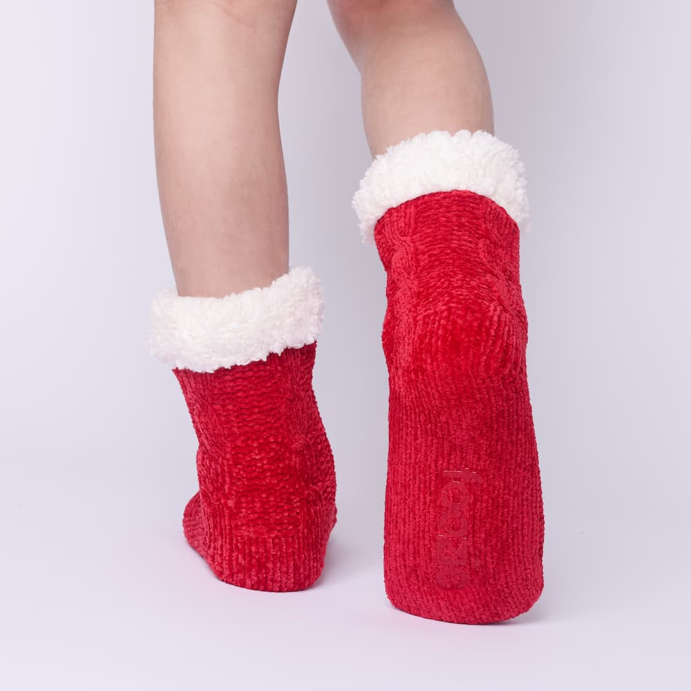The Foozie™ in Red, back view worn in Kids/Small with one foot raised to show the non-slip grips on the sole